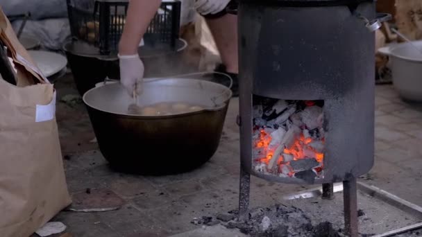 Street Chef prepara papas en una estufa de leña con carbones brillantes. Zoom: — Vídeos de Stock