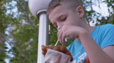 Çocuk Bench 'te oturur, Waffle kupasında kremalı dondurma yer, caddedeki parkta.