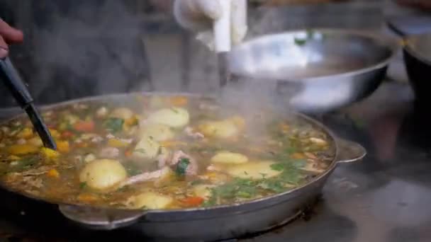 Street Chef Förbereder en grönsaksstuvning utomhus i en gjutjärn Skillet eller Wok — Stockvideo