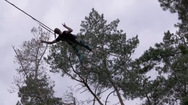 Храбрый канатоходец лежит на веревке с Стражем в Сосновом лесу. Zoom — стоковое видео