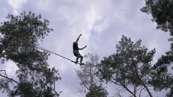 Chauve marcheur effectuant des cascades risquées sur une corde avec assurance dans la forêt de pins — Video