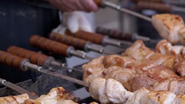 Cocinar Kebab de cerdo jugoso en una parrilla abierta en un patio de comida en una brocheta de metal. — Vídeo de stock