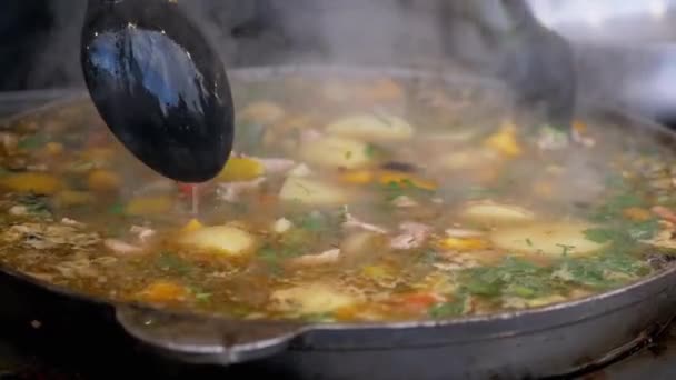 Street Chef bereidt een plantaardige stoofpot buiten in een gegoten ijzeren koekenpan of Wok — Stockvideo