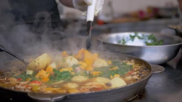 Chef callejero prepara un guiso de verduras al aire libre en una sartén de hierro fundido o Wok — Vídeo de stock