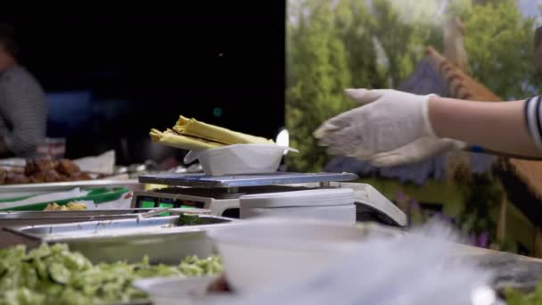 Продавец улиц взвешивает шаурму в пита-хлебе в коробке для обедов по электронной шкале — стоковое видео