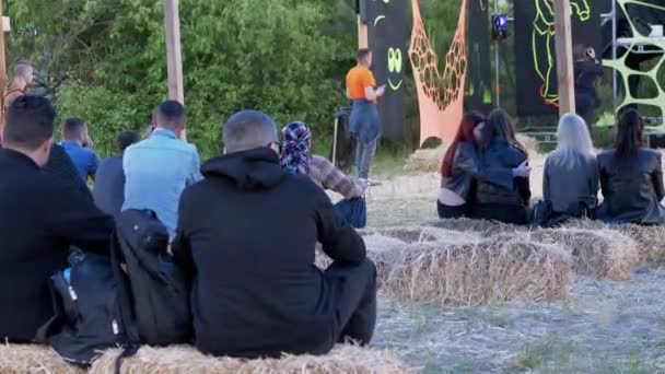 Bakifrån av unga människor sitter i en hö och tittar på en utomhusscen. 4K — Stockvideo