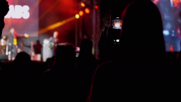 Female Record Video on a Smartphone of a Night Rock Concert on Open Stage (en inglés). 4K — Vídeo de stock