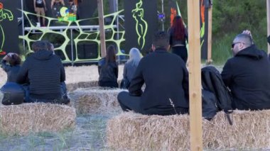 Bir Hay 'da Oturan ve Açık Hava Sahnesine Bakan Gençlerin Arka Bakışı. 4K