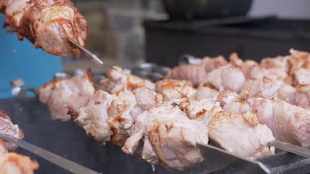 Cocinar Kebab de cerdo jugoso en una parrilla abierta en un patio de comidas en una brocheta de metal. Zoom: — Vídeos de Stock