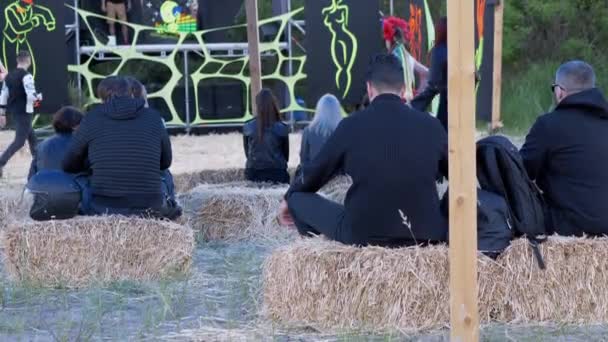 后视镜：年轻人坐在草地上，观看露天舞台。4K — 图库视频影像
