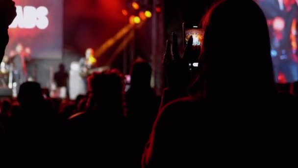 Female Record Video on a Smartphone of a Night Rock Concert on Open Stage (en inglés). 4K — Vídeo de stock