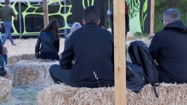 Bakifrån av unga människor sitter i en hö och tittar på en utomhusscen — Stockvideo