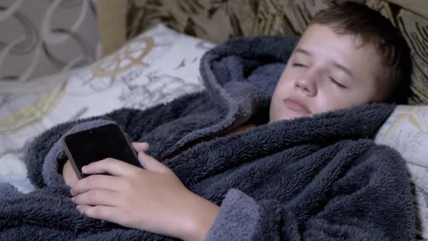 집에서 회색 옷을 입은 사랑 스러운 어린이 Gown Falls Asleep with Smartphone in hands — 비디오