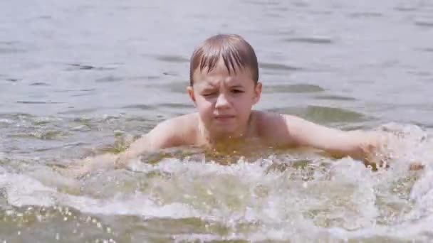 Дитина плазує у воді, річці, створюючи хвилі, сплески, вири. 4K — стокове відео