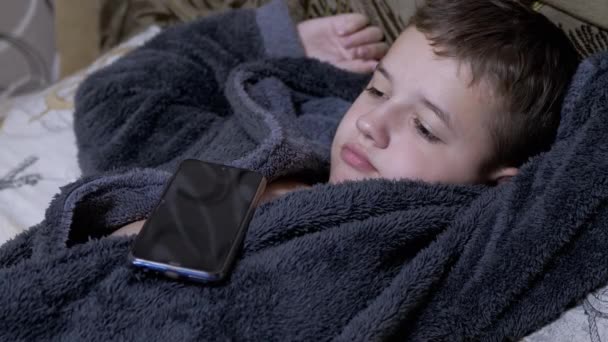 厌倦了的孩子在家里穿衣与智能手机睡着了。4K. — 图库视频影像