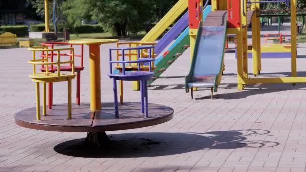 Поворот порожньої багатокольорової каруселі на майданчику в міському парку. Зум — стокове відео