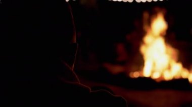 Çocuk Gece Ormanında Oturup Yanan Şenlik Ateşi 'ne Bakıyor. 4K