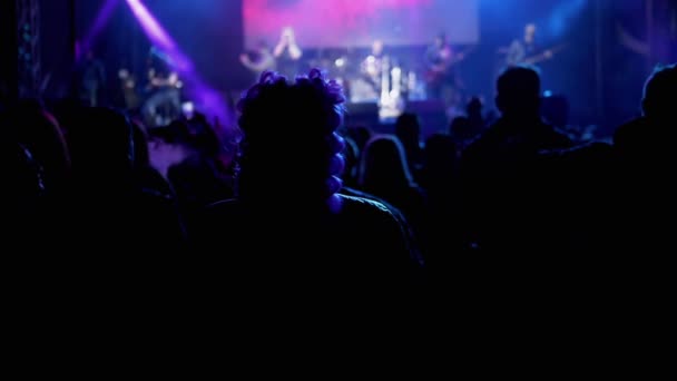 Πλήθος ανθρώπων στέκεται κοντά σε μια ανοιχτή σκηνή Looking a Rock Concert τη νύχτα — Αρχείο Βίντεο