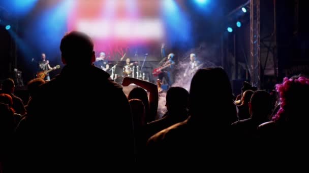 Multitud de personas aplauden a los músicos, levantan los brazos en una escena nocturna abierta — Vídeos de Stock