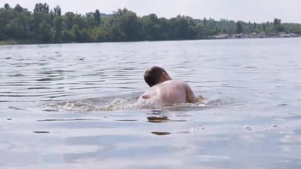 Дитина плазує у воді, річці, створюючи хвилі, сплески, вири. 4K — стокове відео