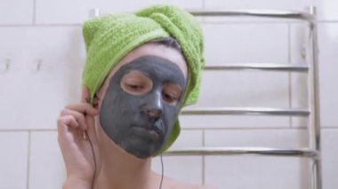 Yüzünde kilden maske olan kız kulaklıkla müzik dinler, tuvalette dans eder.