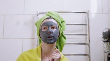 Yüzünde kilden maske olan kız kulaklıkla müzik dinler, tuvalette dans eder.