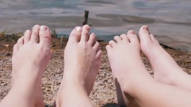 강 근처 샌디 비치 에서 일광욕을 하는 여성 과 어린이의 발 — 비디오