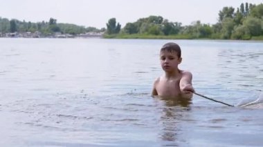 Aktif Çocuk Nehirde Bir Sopayla Oynuyor, Su Dalgaları Yaratıyor, Su Sıçratıyor