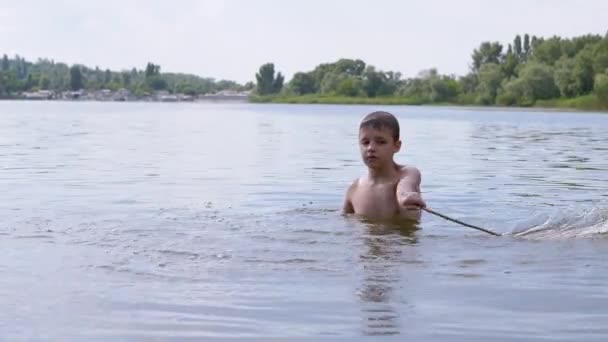 Дітям, які бавляться з молюском у річці, у водних хвилях, які створюють воду, дошкуляє слинка — стокове відео