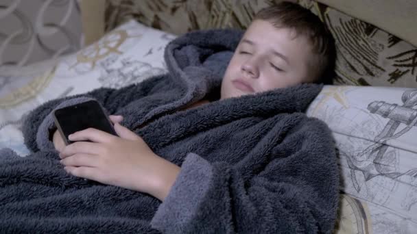 Criança adorável em casa cinza vestido cai dormindo com Smartphone em mãos — Vídeo de Stock