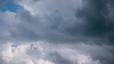 Dramatic timelapse shot of heavy grey storm clouds churning across sky, showing turbulent formations and dark, ominous textures completely covering daylight in an overcast scene of impending bad weather.