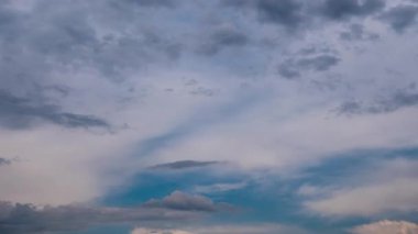Timelapse of dark dramatic clouds moving quickly across stormy sky, showing ominous gray and white formations covering patches of blue, with birds flying past before bad weather.