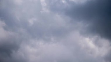 Dynamic time-lapse of fluffy white and grey clouds churning rapidly across a deep blue sky, showing turbulent air currents and constant atmospheric motion, creating an energetic natural background.