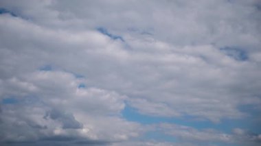 Time-lapse of a soft, overcast sky with sheet-like stratus clouds drifting across frame, revealing small patches of blue as the gray cloud cover moves steadily, creating a calm, muted background.