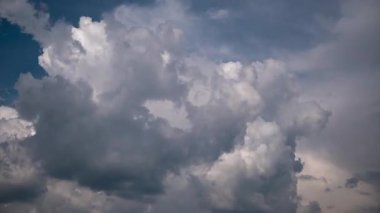 Dramatic time-lapse of bright cumulus clouds transforming into dark, heavy storm clouds, completely covering the blue sky and creating an ominous and turbulent weather front in fast motion.