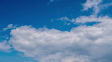 Time-lapse shot of white and grey clouds moving across the sky, gradually dissipating to reveal a clear, deep blue background, symbolizing change or clearing weather in fast motion.