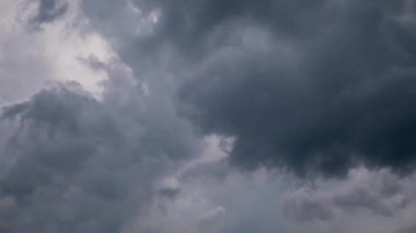 Time-lapse of dark storm clouds gathering in sky, showing dramatic swirling motion, gray cumulus formations covering blue patches, and birds flying before approaching storm.