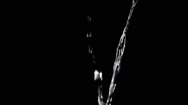 Two Streams of Water with Drops Pour into Empty Space. Black background. A transparent stream of water with streams joins into a funnel. Splashes, drops. Abstraction, texture, lighting. Slow motion.