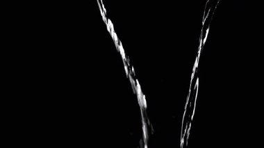 Two Streams of Water with Drops Pour into Empty Space. Black background. A transparent stream of water with streams joins into a funnel. Splashes, drops. Abstraction, texture, lighting. Slow motion.
