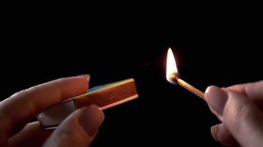 Karanlık Oda 'da kibrit kutusuyla yanan kibrit. Kadın el ışıklandırması. Parlak alev ateşiyle yanan kibrit. Oda ışıkları. Elektrik kesintisi. Ağır çekim. Yakın plan..