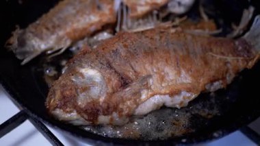 Altın sarısı kahverengi balıklar tavada cızırdıyor ve kızarıyor. Ağız sulandıran bir aşçılık süreci sergiliyor.