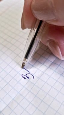 Bir tükenmez kalemin dikey, aşırı yakın plan, mavi mürekkepli, el yazısıyla 31 Ekim tarihini beyaz şebeke kağıdına yazmış. Sayfa boyunca ilerlerken parmaklar saydam kalemi tutar.