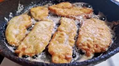 Dayak yemiş balık filetoları kızgın, köpüren yağlar içinde kızgın demir bir tavada kızarıyor. Mutfaktaki ev yemeği hazırlama sırasında lezzetli deniz ürünlerinde altın rengi, çıtır çıtır bir doku gelişir..