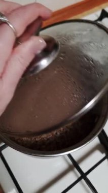 Kadın eli, pişmiş karabuğdayı ortaya çıkaran bir tencerenin kapağını kaldırır. Tencere, ev mutfağındaki beyaz bir gaz ocağının üzerinde duruyor. Yeni pişmiş kasha 'dan sıcak buhar yükseliyor..