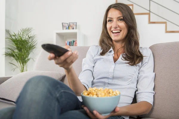 Young woman with popcorn watching the tv