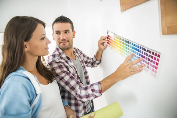 Young couple choosing paint color and pent paper — Stock Photo, Image