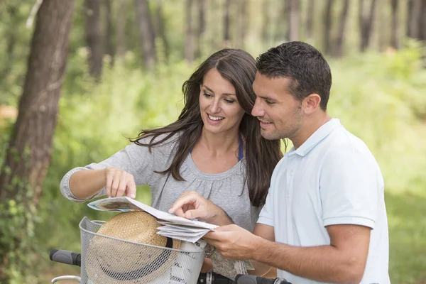 Pareja joven con mapa y bicicleta — Foto de Stock