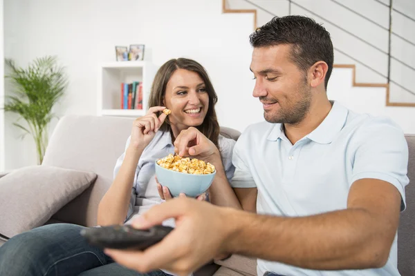 Jovem casal com pipocas assistindo filme em casa — Fotografia de Stock