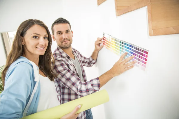 Pareja joven eligiendo color de pintura y papel reprimido —  Fotos de Stock