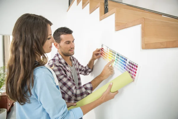 Young couple choosing paint color and pent paper — Stock Photo, Image